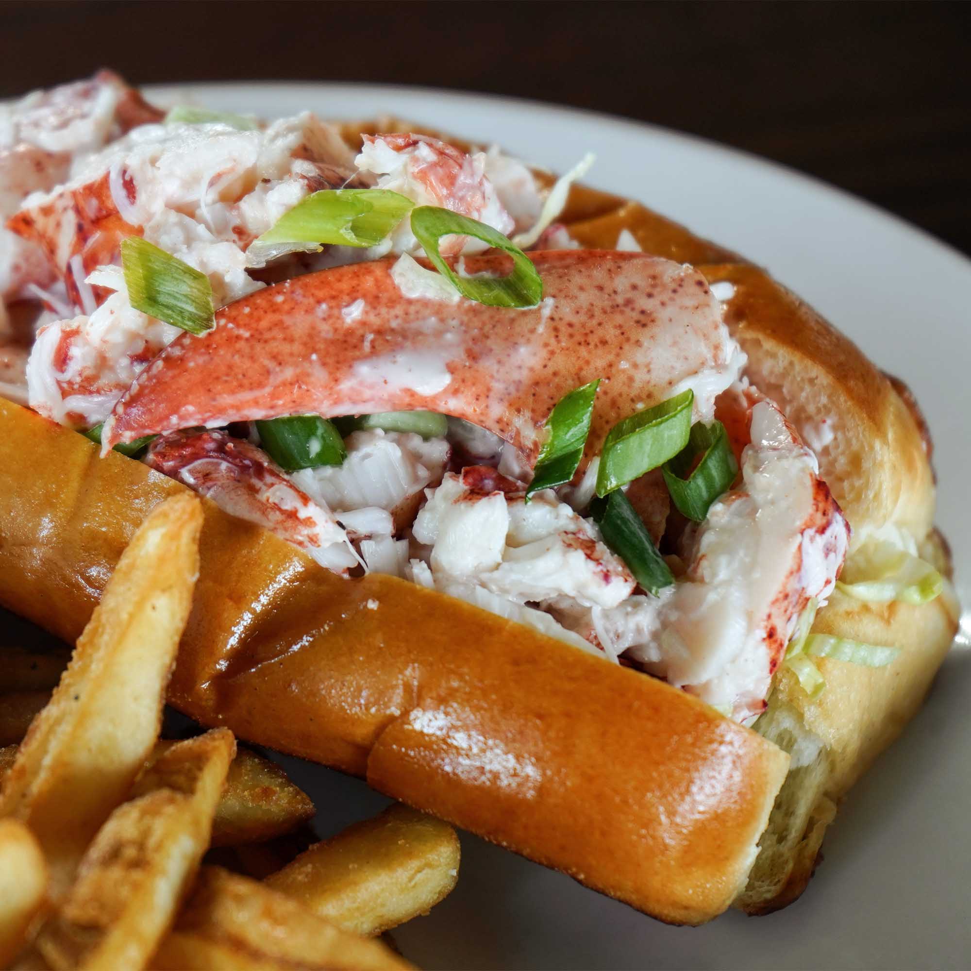 Image of a lobster roll and French fries on a plate.