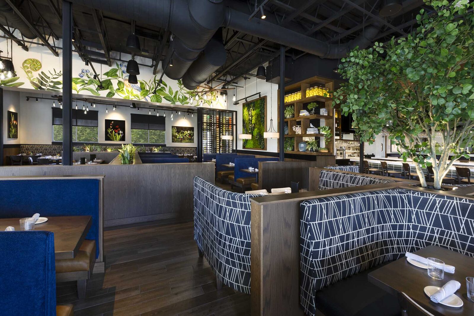 Lively restaurant interior at Burtons Grill & Bar with modern décor, vibrant greenery, and cozy dining booths.
